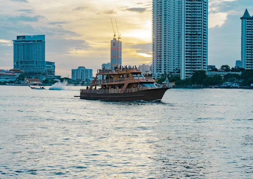 a boat traveling through the water in front of tall buildings